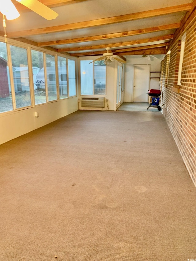 unfurnished sunroom with ceiling fan, beamed ceiling, and a wall mounted AC