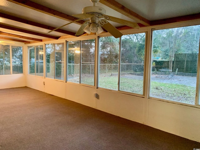 unfurnished sunroom featuring a healthy amount of sunlight, beamed ceiling, and ceiling fan