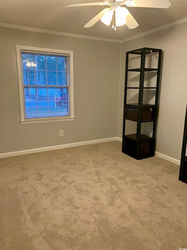 empty room with carpet floors, ornamental molding, a ceiling fan, and baseboards