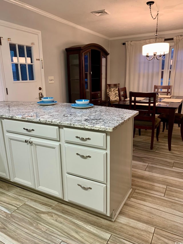 kitchen featuring hanging light fixtures, light stone countertops, ornamental molding, and a notable chandelier