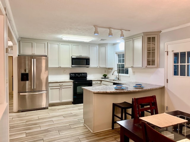 kitchen featuring stainless steel appliances, a peninsula, a sink, wood tiled floor, and glass insert cabinets