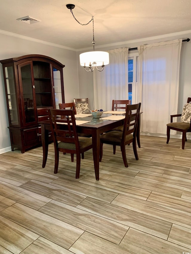 dining space featuring visible vents, wood tiled floor, ornamental molding, and a chandelier