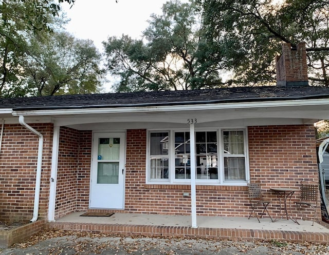 exterior space with brick siding and a chimney