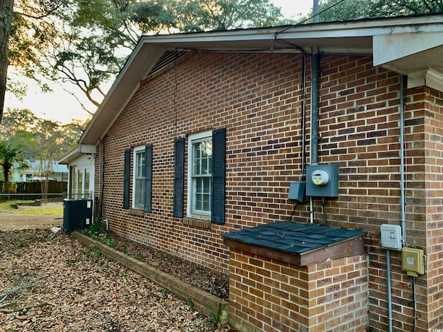 view of home's exterior featuring brick siding, cooling unit, and fence