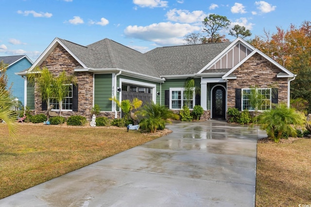 craftsman-style home with driveway, stone siding, an attached garage, and a front lawn