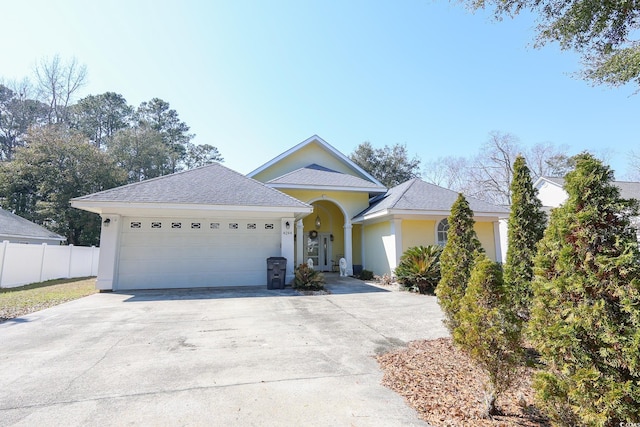 ranch-style home featuring a garage, concrete driveway, fence, and stucco siding