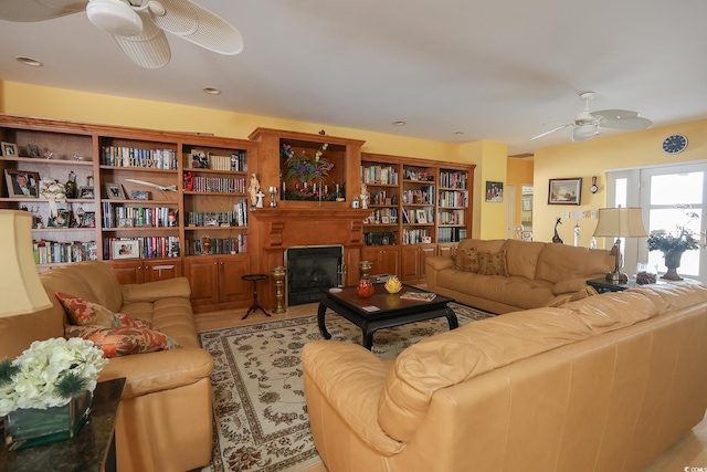 living area featuring a ceiling fan and a glass covered fireplace