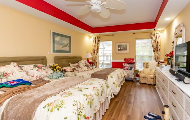 4244 Luck Ave, Little River, SC 29566 - bedroom with wood finished floors, a tray ceiling, and ceiling fan