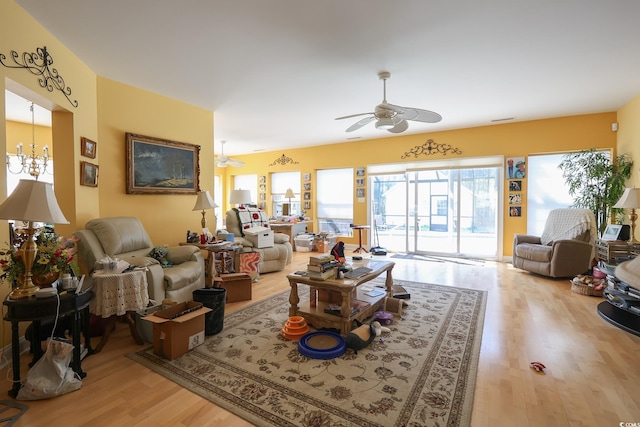 living area featuring ceiling fan with notable chandelier, visible vents, and wood finished floors