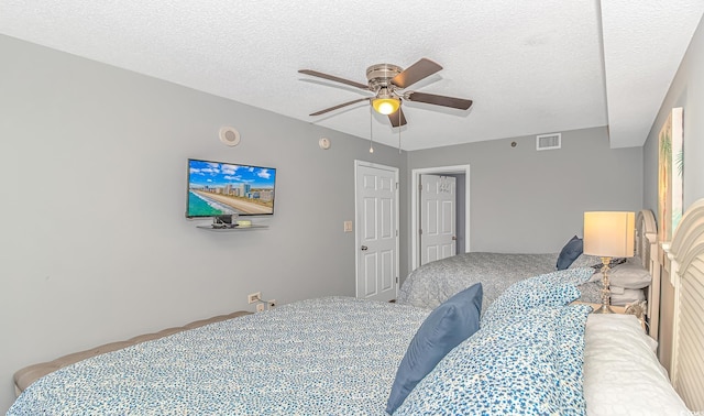 bedroom featuring carpet flooring, a textured ceiling, visible vents, and a ceiling fan
