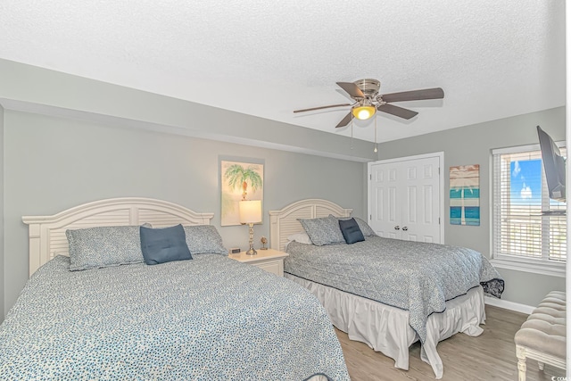 bedroom with a closet, light wood-type flooring, a textured ceiling, baseboards, and ceiling fan