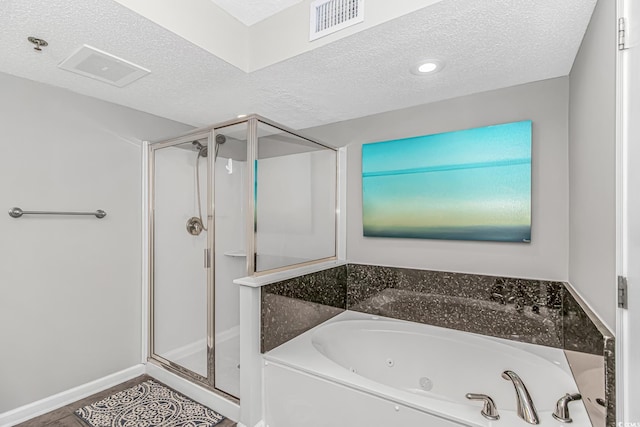 bathroom featuring a textured ceiling, a stall shower, and a jetted tub