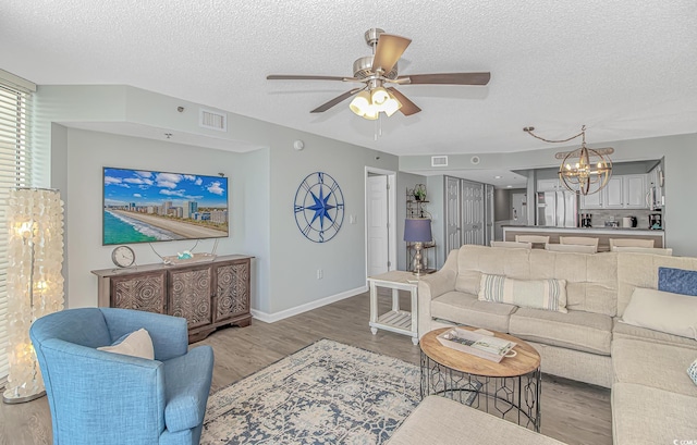living area with a textured ceiling, light wood-style flooring, and visible vents
