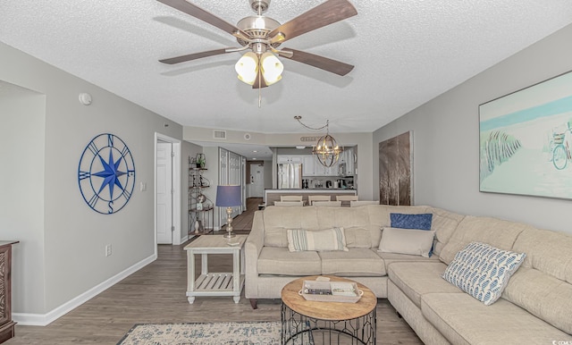 living room featuring a chandelier, wood finished floors, a textured ceiling, a ceiling fan, and baseboards