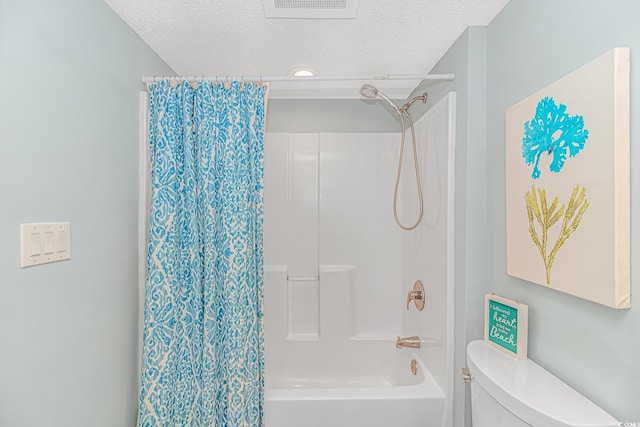 bathroom with a textured ceiling, toilet, and shower / bath combo