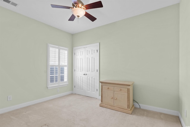 empty room featuring baseboards, visible vents, ceiling fan, and light colored carpet