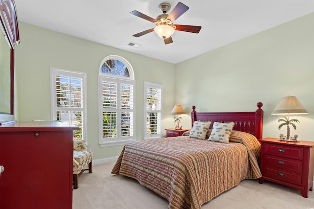 bedroom featuring ceiling fan, visible vents, baseboards, and light colored carpet