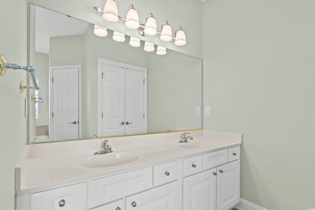 full bathroom featuring double vanity, a sink, and baseboards