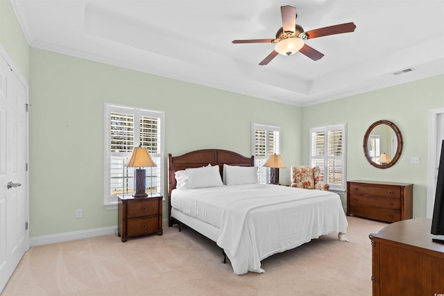 bedroom with light colored carpet, a tray ceiling, visible vents, and baseboards