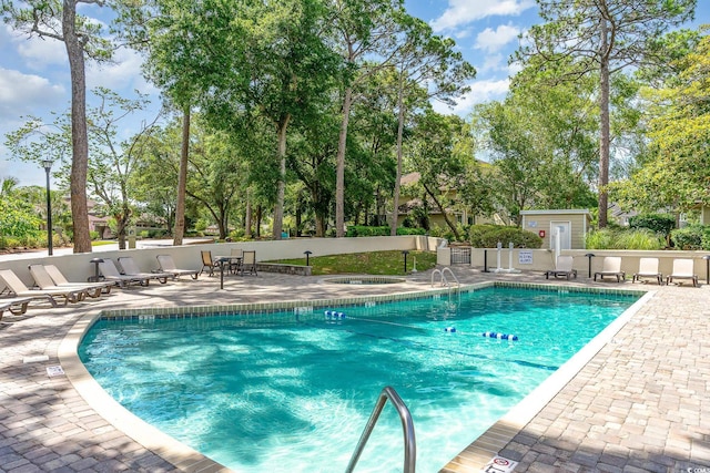 community pool with a patio area and fence