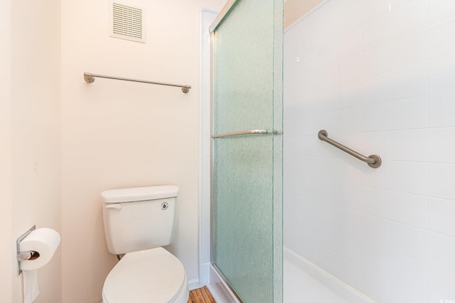 bathroom with visible vents, a tile shower, and toilet