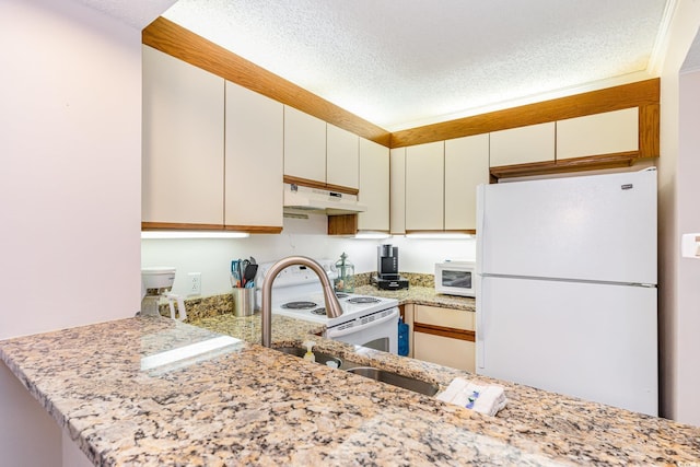 kitchen with a textured ceiling, under cabinet range hood, a peninsula, white appliances, and white cabinets