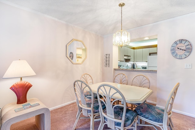 carpeted dining room with ornamental molding, a textured ceiling, baseboards, and an inviting chandelier