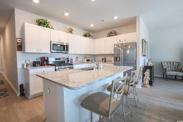 kitchen featuring visible vents, a sink, recessed lighting, stainless steel appliances, and a breakfast bar area