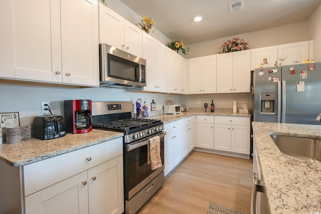 kitchen featuring white cabinets, light wood-style floors, appliances with stainless steel finishes, and a sink