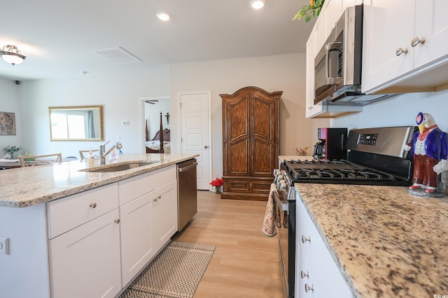 kitchen with light wood-style flooring, white cabinets, appliances with stainless steel finishes, and a sink