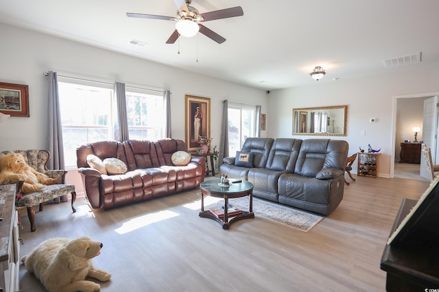 living room featuring light wood-style floors, visible vents, and ceiling fan