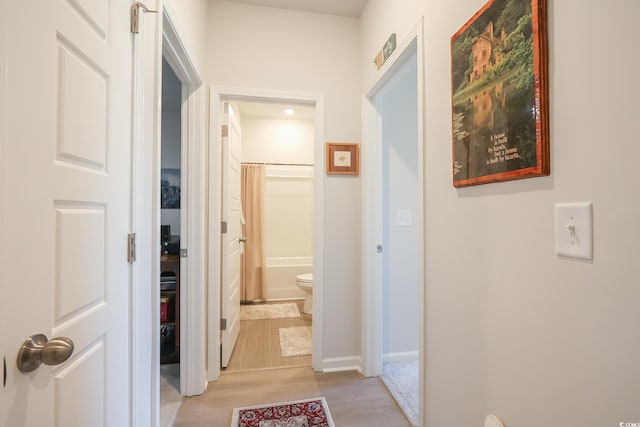 hall featuring baseboards and light wood-style flooring