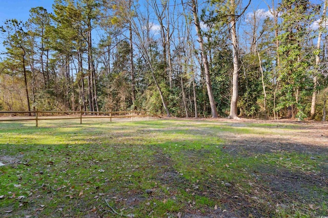 view of yard featuring a forest view and fence