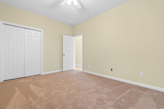 unfurnished bedroom featuring ceiling fan, a closet, carpet, and baseboards