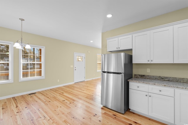 kitchen featuring light wood-style floors, visible vents, white cabinets, and freestanding refrigerator