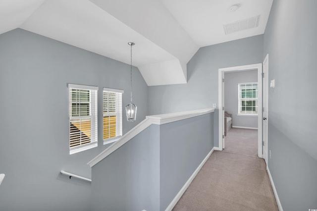 hall featuring visible vents, lofted ceiling, an inviting chandelier, an upstairs landing, and carpet floors