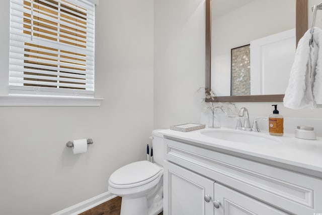 bathroom featuring baseboards, vanity, toilet, and wood finished floors