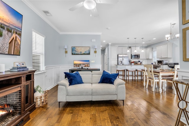 living room with crown molding, wainscoting, plenty of natural light, and dark wood-type flooring