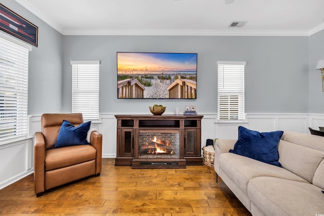 living room featuring visible vents, crown molding, a lit fireplace, and wood finished floors