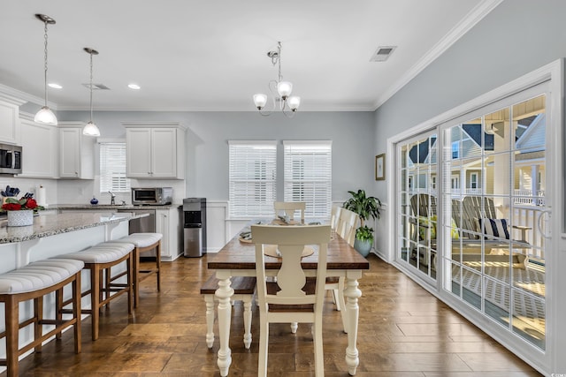 dining area with ornamental molding, dark wood finished floors, visible vents, and an inviting chandelier