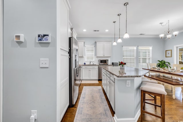 kitchen with a center island, crown molding, white cabinets, stainless steel fridge, and a kitchen breakfast bar