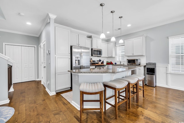 kitchen with white cabinets, dark wood-style floors, a kitchen island, stainless steel appliances, and crown molding