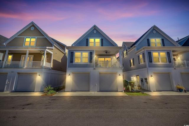 coastal inspired home with a garage, a balcony, driveway, and a ceiling fan