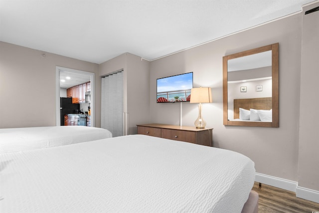 bedroom with freestanding refrigerator, a closet, baseboards, and wood finished floors