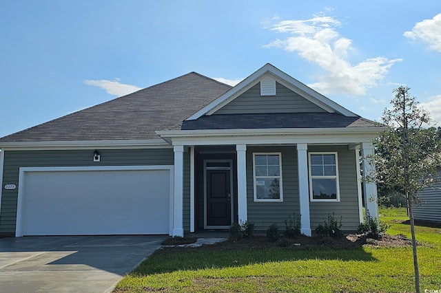 view of front of house featuring driveway, a front lawn, a garage, and a shingled roof