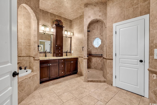 full bath featuring a walk in shower, a garden tub, double vanity, tile walls, and a sink