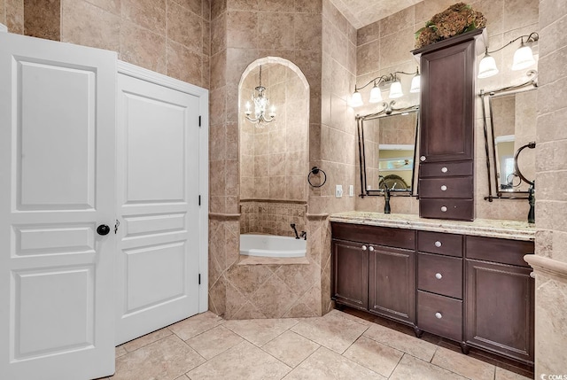 bathroom with a relaxing tiled tub, tile walls, vanity, and tile patterned flooring