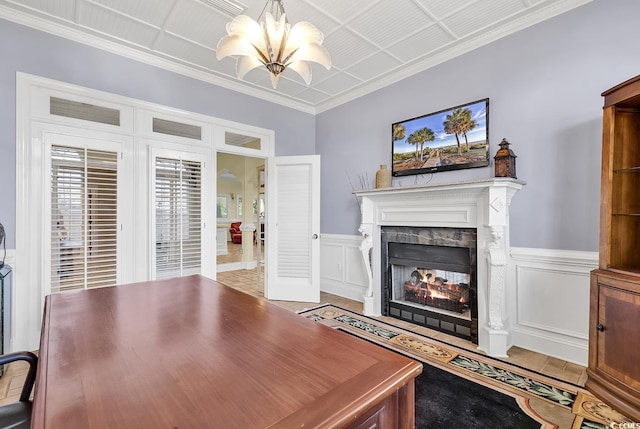 interior space with a notable chandelier, a decorative wall, wainscoting, crown molding, and a multi sided fireplace