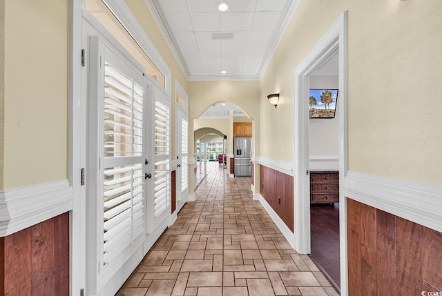 hall featuring arched walkways, a wainscoted wall, recessed lighting, and ornamental molding