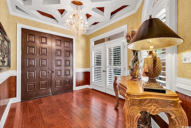 foyer with coffered ceiling, an inviting chandelier, hardwood / wood-style floors, and wainscoting